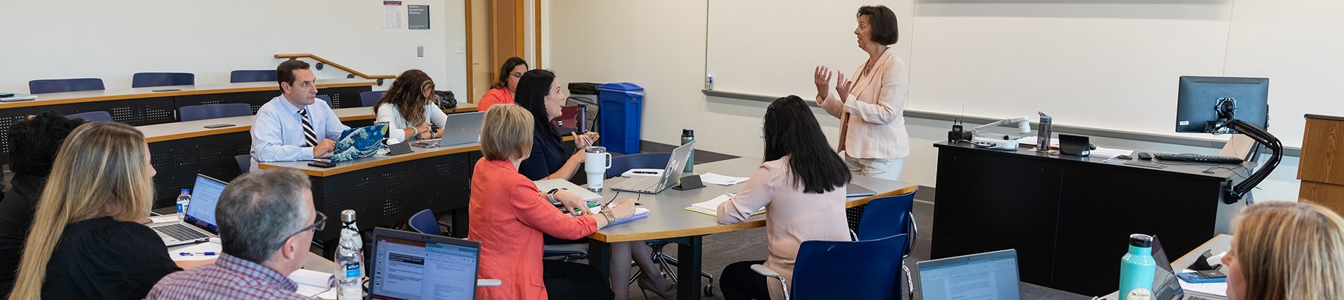 Adults sit in a classroom listening to an instructor.