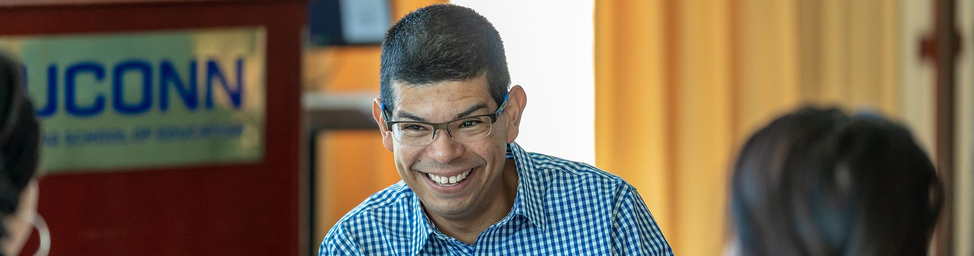 An adult student of color smiles at two classmates.