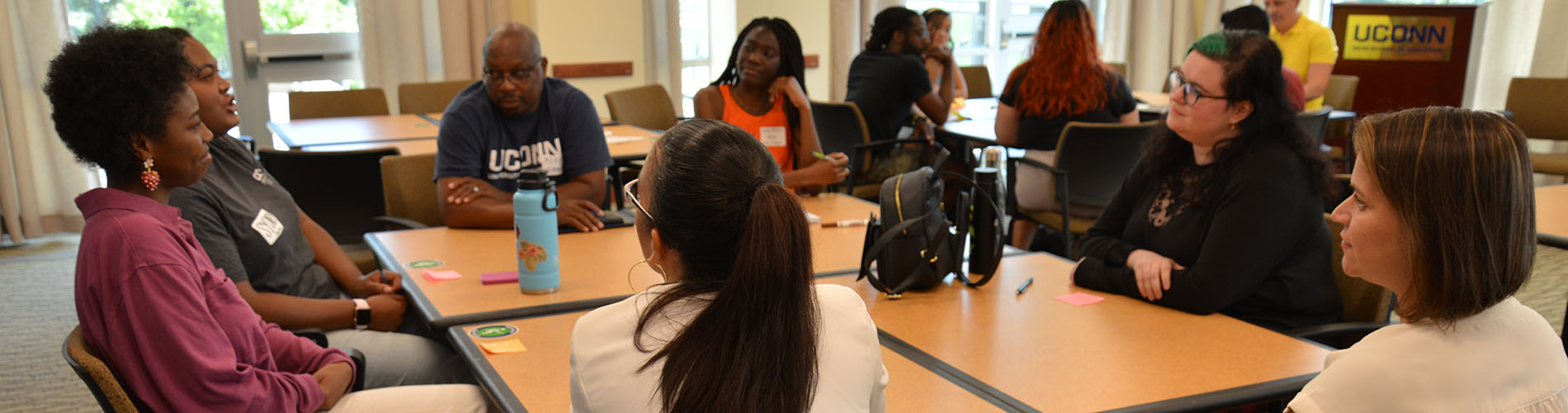 A room full of adult students, who sit at large tables.